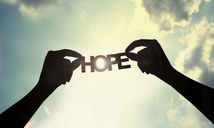 Hope Photo: Two hands hold letters towards the sky that spell the word hope as sun rays beam down.